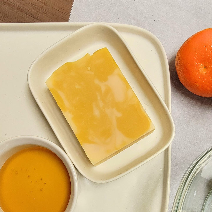 Experience the perfect balance of nourishment and refreshment with our Honey Tangerine Handmade Soap. Made in small batches using the cold-process method, this soap is packed with hydrating honey, soothing aloe vera juice, and purifying kaolin clay. The bright citrus aroma of tangerine, litsea cubeba, and bergamot essential oils provides an energizing boost, while silk fibers add a touch of luxury to every wash.